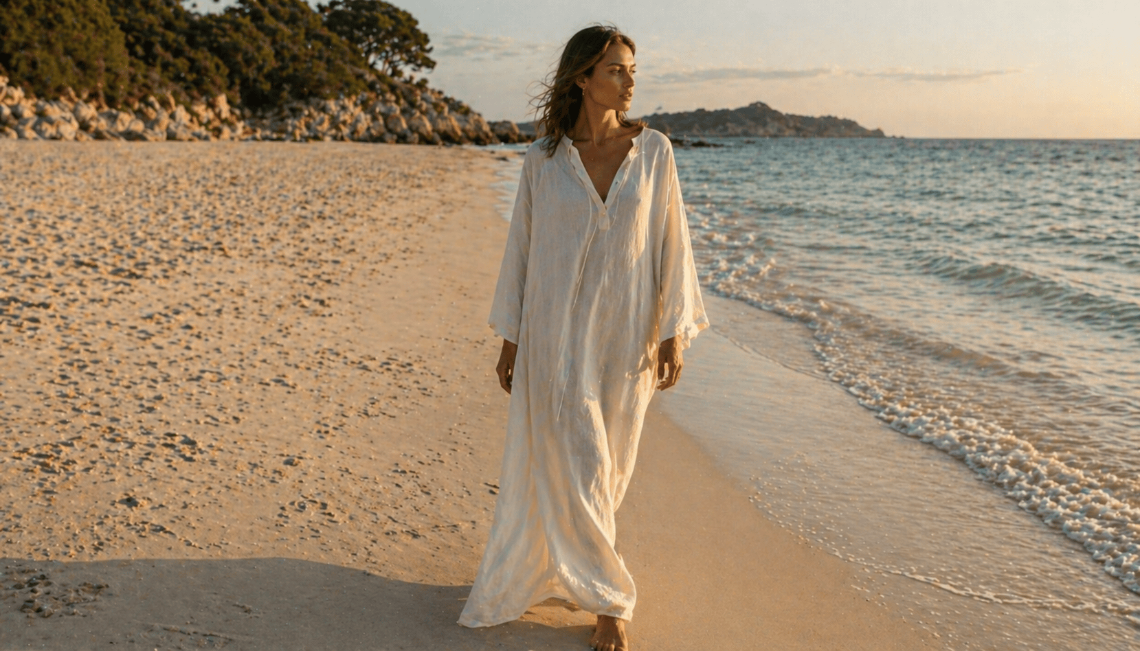 South-Asian woman walking a sun-bleached Spanish Banks path in an unstructured European-linen column dress in pale stone, raw-edge hem swinging at the ankle